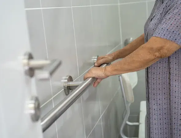 Older adult using a securely mounted bathroom grab bar for support