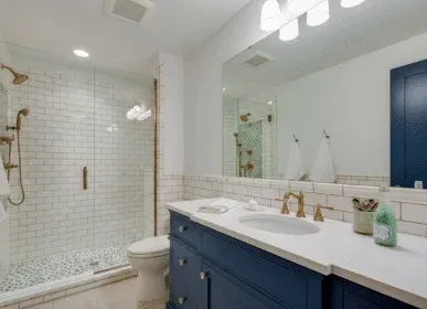 Guest bath with navy vanity, brass fixtures and subway tile shower