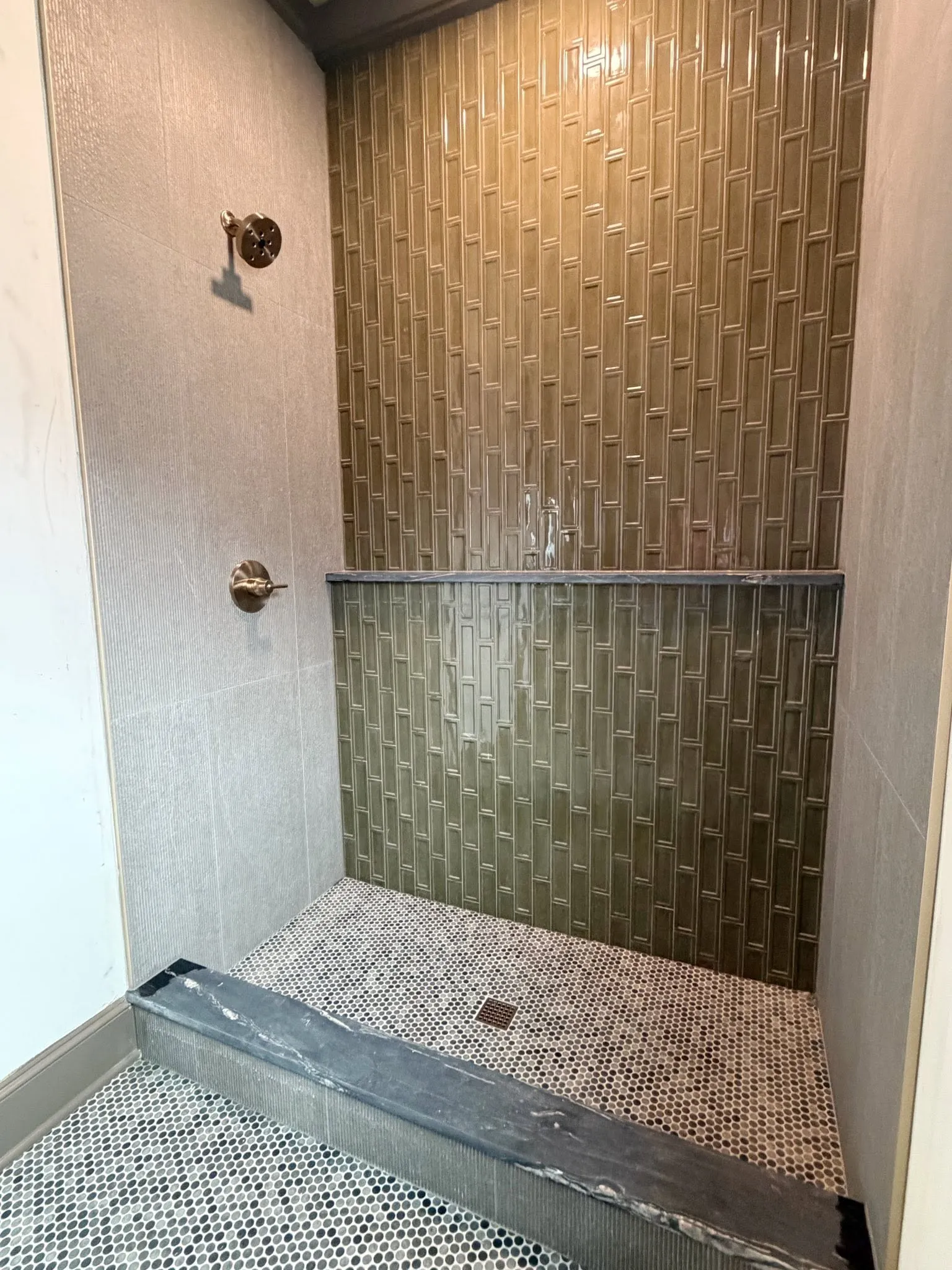 Walk-in shower with brown vertical accent tile and penny mosaic flooring
