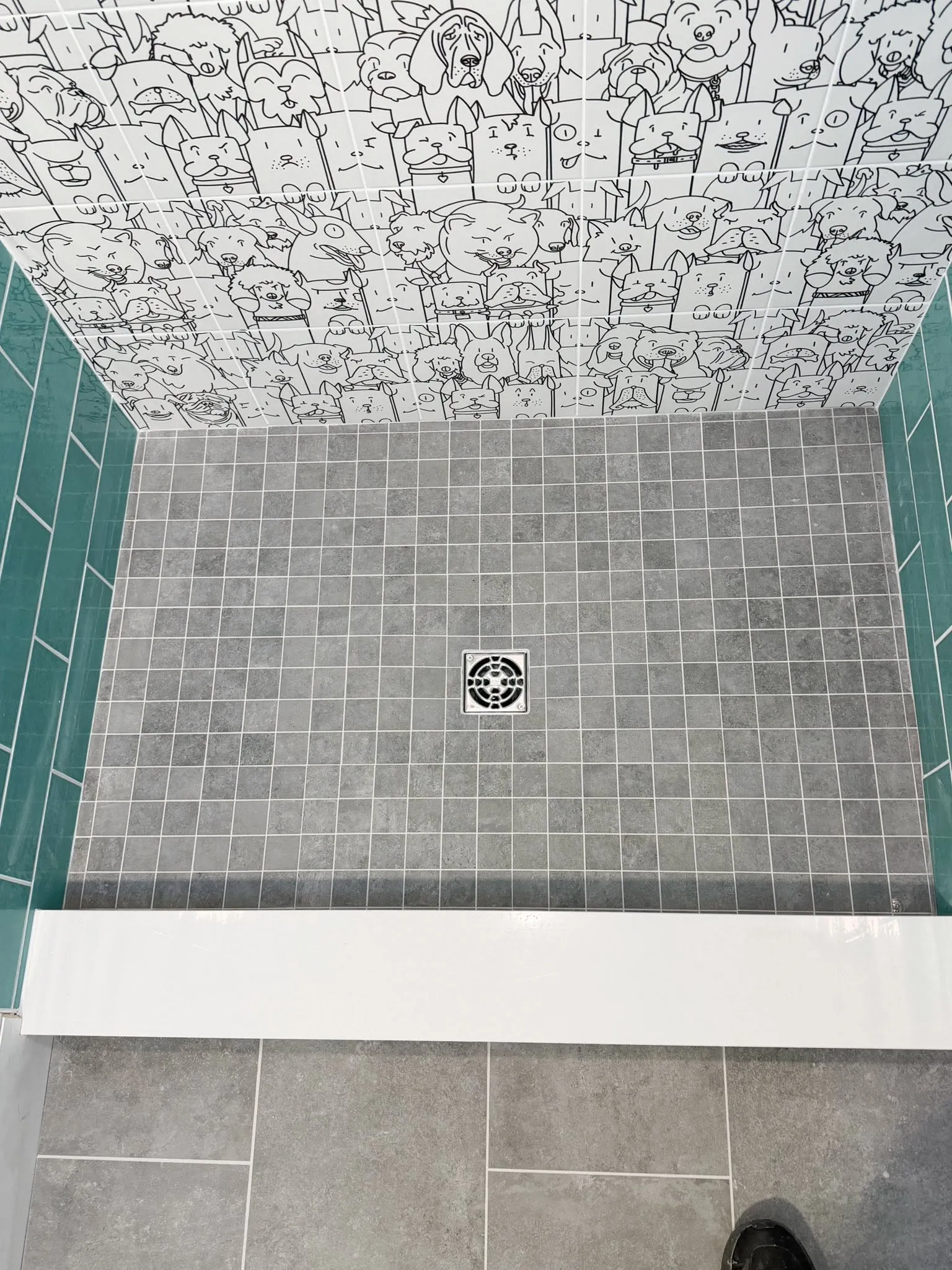Custom shower floor with gray mosaic tile and a playful dog-pattern accent wall