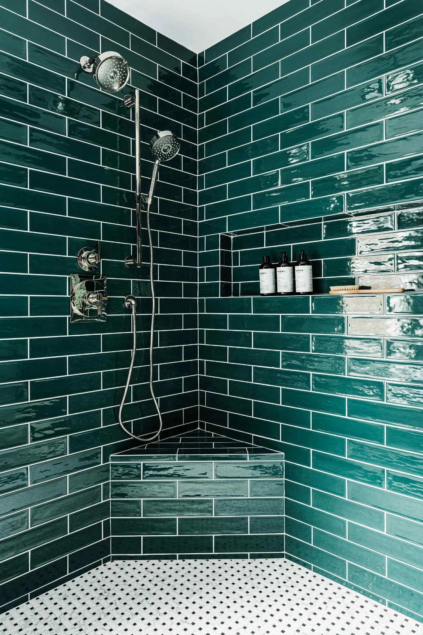 Custom walk-in shower with glossy green subway tile, a tiled corner bench, and dual showerheads