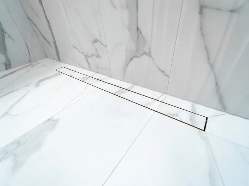 Linear shower drain installed in a marble-look doorless shower floor